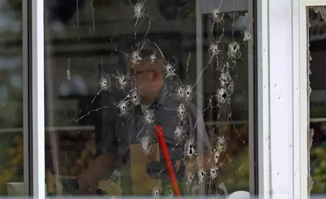 Damage can be seen to a front window law enforcement officers work the scene of a shooting at the Mad Butcher grocery store in Fordyce, Ark., Friday, June 21, 2024. (Colin Murphey/Arkansas Democrat-Gazette via AP)