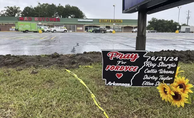 A sign in memory of the four victims killed in a mass shooting at the Mad Butcher grocery store sits near the store's parking lot in Fordyce, Ark., on Wednesday, June 26, 2024. (AP Photo/Andrew DeMillo)