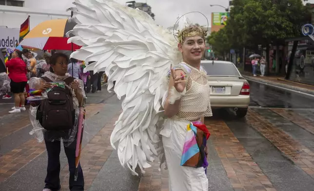 A reveler, wearing angel wings, strikes a pose while crossing the street before the start of a Gay Pride parade marking the culmination of LGBTQ+ Pride month, in Guatemala City, Saturday, June 29, 2024. (AP Photo/Moises Castillo)