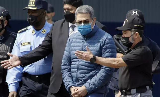 FILE - Former Honduran President Juan Orlando Hernandez, second from right, is taken in handcuffs to a waiting aircraft as he is extradited to the United States, at an Air Force base in Tegucigalpa, Honduras, April 21, 2022. Hernandez was sentenced Wednesday, June 26, 2024 in New York, for his conviction on charges that he enabled drug traffickers to use his military and national police force to help get tons of cocaine into the United States. (AP Photo/Elmer Martinez, File)