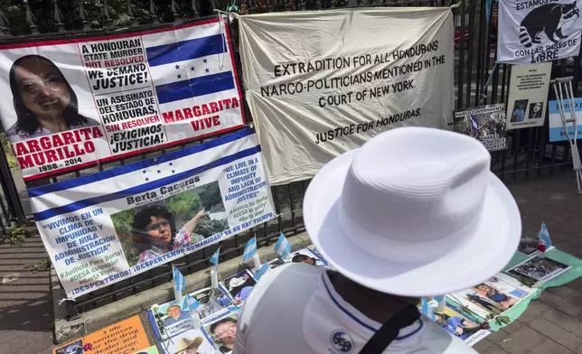 Protestors signs and images victims of Honduran drug traffickers outside Federal court, Wednesday, June 26, 2024, in New York. Former Honduran President Juan Orlando Hernandez is scheduled for sentencing after being convicted in New York of conspiring with drug traffickers, his military and police to enable tons of cocaine to reach the United States. (AP Photo/John Minchillo)