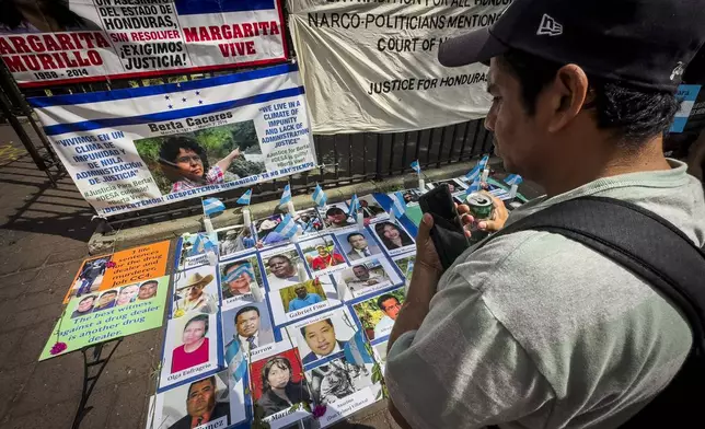 Protestors signs and images victims of Honduran drug traffickers outside Federal court, Wednesday, June 26, 2024, in New York. Former Honduran President Juan Orlando Hernandez is scheduled for sentencing after being convicted in New York of conspiring with drug traffickers, his military and police to enable tons of cocaine to reach the United States. (AP Photo/John Minchillo)