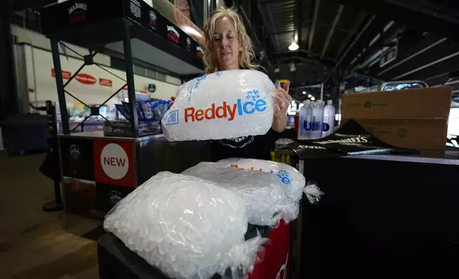 Cheryl Batch picks up a bag of ice to use to cool beverages at a stand on the main concourse of Coors Field before the Colorado Rockies host the Pittsburgh Pirates in a baseball game Sunday, June 16, 2024, in Denver. (AP Photo/David Zalubowski)