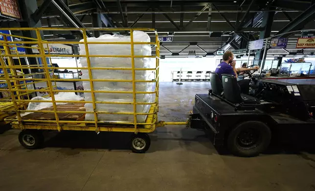 A tug driver pulls a trailer of bags of ice for use in concession stands on the main concourse of Coors Field before the Colorado Rockies host the Pittsburgh Pirates in a baseball game Sunday, June 16, 2024, in Denver. (AP Photo/David Zalubowski)