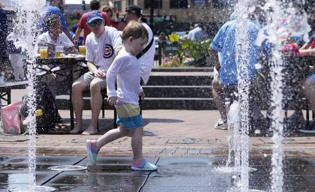 A kid cools off at Gallagher Way park fountain during hot weather in Chicago, Sunday, June 16, 2024. (AP Photo/Nam Y. Huh)