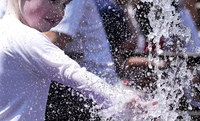 A boy cools off at a fountain during hot weather in Chicago, Sunday, June 16, 2024. (AP Photo/Nam Y. Huh)