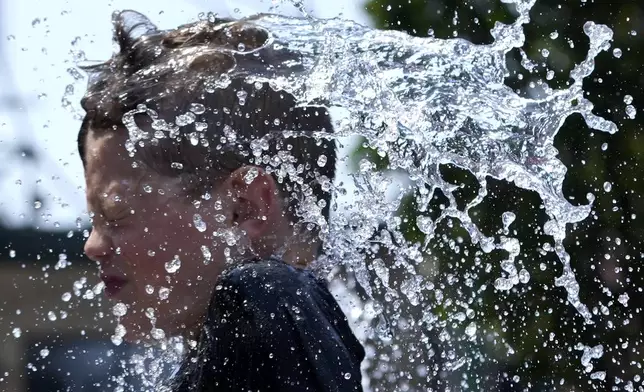 A boy cools off at a fountain during hot weather in Chicago, Sunday, June 16, 2024. (AP Photo/Nam Y. Huh)