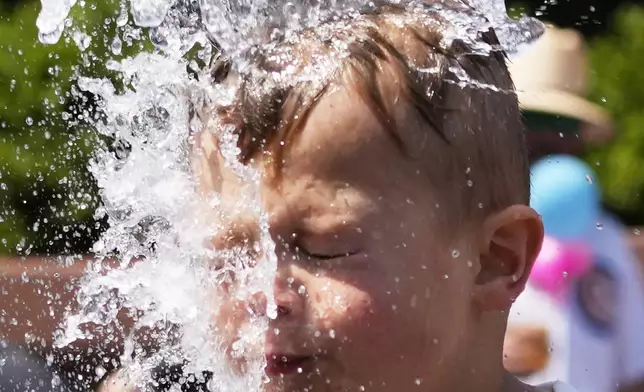 A boy cools off at a fountain during hot weather in Chicago, Sunday, June 16, 2024. (AP Photo/Nam Y. Huh)