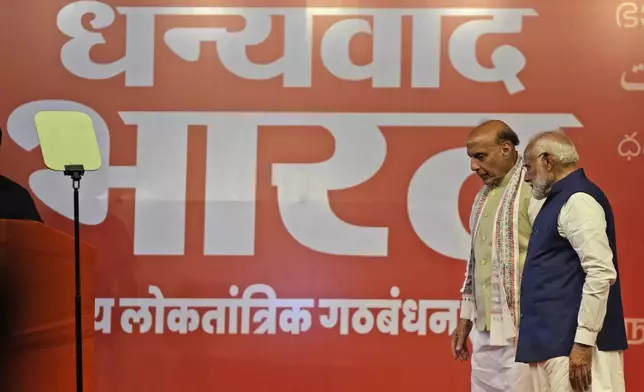 Prime Minister Narendra Modi, right, with Defense Minister Rajnath Singh leaves after addressing supporters at the Bharatiya Janata Party (BJP) headquarters, in New Delhi, India, Tuesday, June 4, 2024. On the banner it's written in local language 'Thank you Bharat". (AP Photo/Manish Swarup)