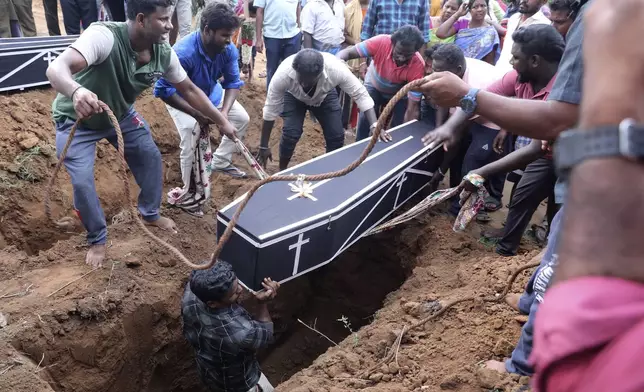 Men lower a coffin into a grave pit to bury a man, who died after drinking illegally brewed liquor, in Kallakurichi district of the southern Indian state of Tamil Nadu, India, Thursday, June 20, 2024. The state's chief minister M K Stalin said the 34 died after consuming liquor that was tainted with methanol, according to the Press Trust of India news agency. (AP Photo/R. Parthibhan)