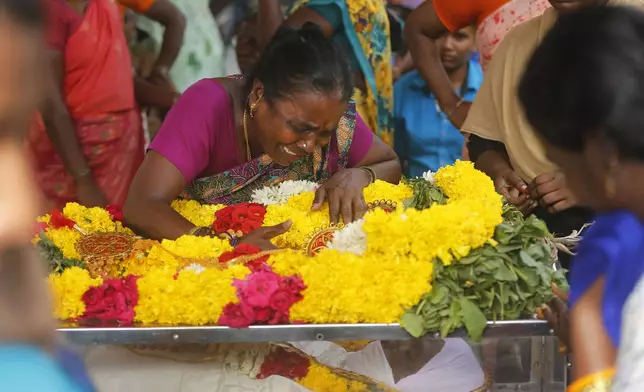 A relative of a man, who died after drinking illegally brewed liquor, cries over a casket containing his body in Kallakurichi district of the southern Indian state of Tamil Nadu, India, Thursday, June 20, 2024. The state's chief minister M K Stalin said the 34 died after consuming liquor that was tainted with methanol, according to the Press Trust of India news agency. (AP Photo/R. Parthibhan)