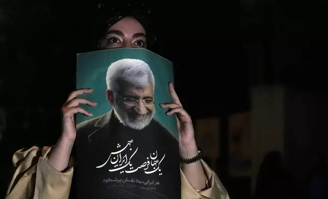 A supporter of Saeed Jalili, a candidate for the presidential election, holds up his poster during a campaign gathering in Tehran, Iran, Wednesday, June 26, 2024. (AP Photo/Vahid Salemi)