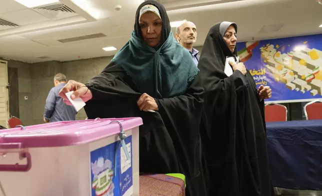 A woman casts her vote during the presidential election at a polling station inside the Iranian Embassy in Baghdad, Iraq, Friday, June 28, 2024. Iranians were voting Friday in a snap election to replace the late President Ebrahim Raisi, killed in a helicopter crash last month, as public apathy has become pervasive in the Islamic Republic after years of economic woes, mass protests and tensions in the Middle East. (AP Photo/Hadi Mizban)