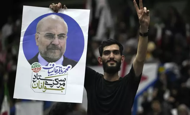 A supporter of Iran's parliament speaker Mohammad Bagher Qalibaf, the most prominent hard-line candidate for the presidential election, holds up his poster in a campaign gathering in Tehran, Iran, Wednesday, June 26, 2024. (AP Photo/Vahid Salemi)