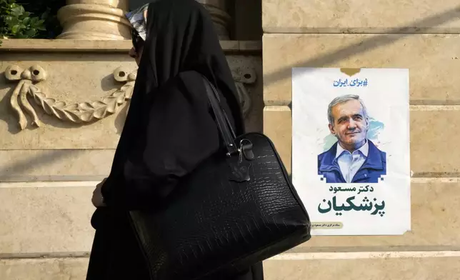 An Iranian woman walks past a poster of reformist candidate for the presidential election Masoud Pezeshkian, in Tehran, Iran, Saturday, June 29, 2024. On July 5, Iran will hold a runoff presidential election pitting a little-known reformist against a hard-line former nuclear negotiator after results released Saturday showed the lowest-ever poll turnout in the Islamic Republic's history. (AP Photo/Vahid Salemi)