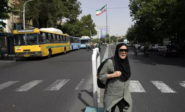 A woman crosses a street in downtown Tehran, Iran, Saturday, June 29, 2024. Iran will hold a runoff presidential election to replace the late hard-line President Ebrahim Raisi after an initial vote saw the top candidates not secure an outright win in the lowest turnout poll ever held in the Islamic Republic by percentage. (AP Photo/Vahid Salemi)