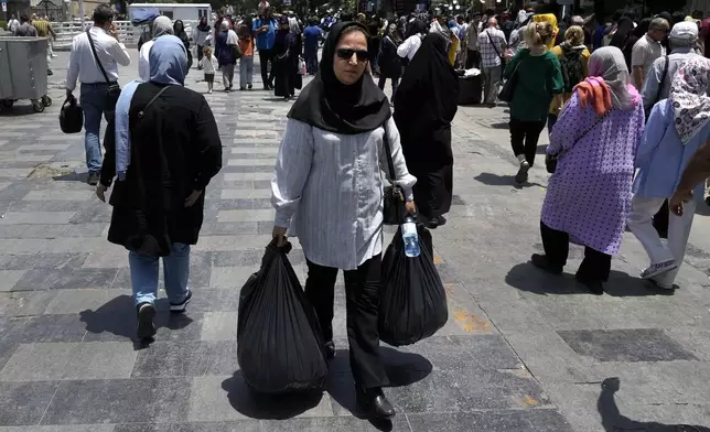 A woman carries her shopping in the old main bazaar of Tehran, Iran, Thursday, June 13, 2024. The rise of the “Hamster Kombat” app in Iran highlights a harsher truth facing the Islamic Republic's economy ahead of its presidential election this week to replace the late President Ebrahim Raisi, who died in a helicopter crash in May. (AP Photo/Vahid Salemi)