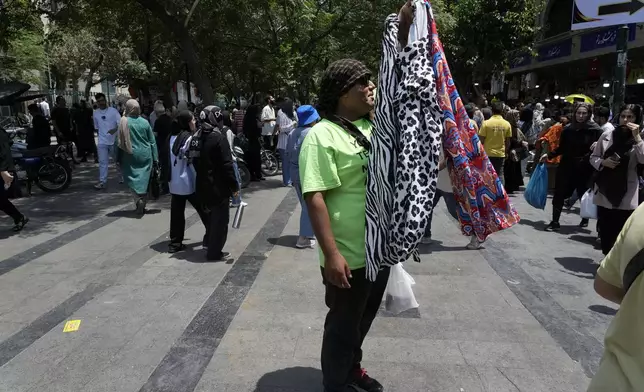 A vendor advertises women's cloths in the old main bazaar of Tehran, Iran, Thursday, June 13, 2024. The rise of the “Hamster Kombat” app in Iran highlights a harsher truth facing the Islamic Republic's economy ahead of its presidential election this week to replace the late President Ebrahim Raisi, who died in a helicopter crash in May. (AP Photo/Vahid Salemi)