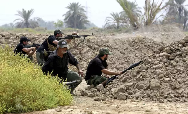 FILE - Iraq Shiite fighters prepare to fight militants from the extremist Islamic State group in Jurf al-Sakhar, 43 miles (70 kilometers) south of Baghdad, Iraq, Aug 18, 2014. Ten years after the Islamic State group declared its caliphate in large parts of Iraq and Syria, the extremists now control no land, have lost many prominent founding leaders and are mostly away from the world news headlines. (AP Photo/Hadi Mizban, File)