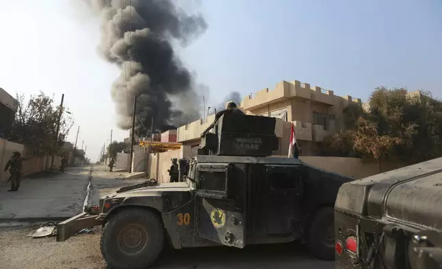 FILE - Smoke rises as Iraq's elite counterterrorism forces fight against Islamic State militants to regain control of al-Bakr neighborhood in Mosul, Iraq, Dec. 12, 2016. Ten years after the Islamic State group declared its caliphate in large parts of Iraq and Syria, the extremists now control no land, have lost many prominent founding leaders and are mostly away from the world news headlines. (AP Photo/Hadi Mizban, File)
