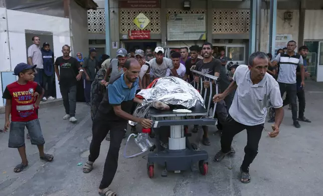 Palestinians carry the body of a man killed in the Israeli bombardment of the Gaza Strip to a hospital morgue in Khan Younis, southern Gaza Strip, Monday, June 24, 2024. (AP Photo/Jehad Alshrafi)