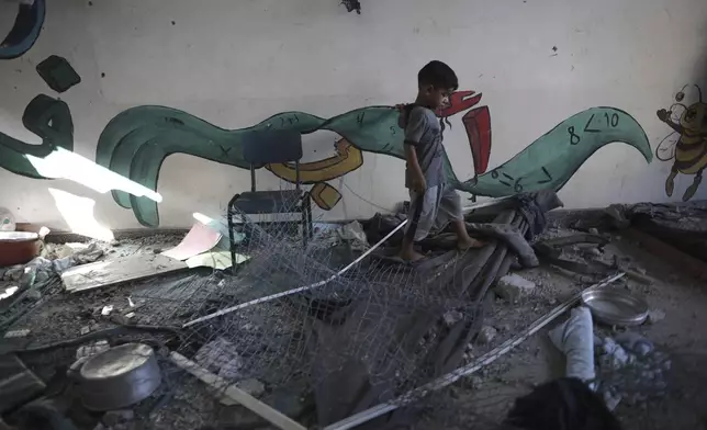 A Palestinian child navigates through heavy damage to a UNRWA school sheltering displaced persons the day after a nearby house was targeted by Israeli bombardment in Khan Younis, southern Gaza Strip, Friday, June 21, 2024. (AP Photo /Jehad Alshrafi)