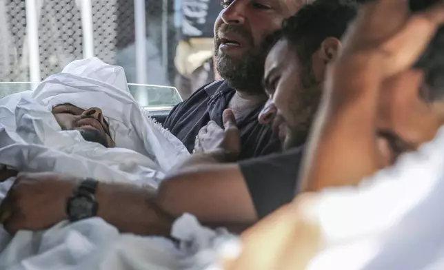 Muhammad al-Habil, killed along with his uncle Abdul Muti al-Habil, is cradled by his father on the way to the funeral of the two men, in Deir al Balah, Gaza Strip, Friday June 14, 2024. The two men were killed while fishing in the sea when Israeli gunboats opened fire on them. (AP Photo/Mohammad Hajjar)