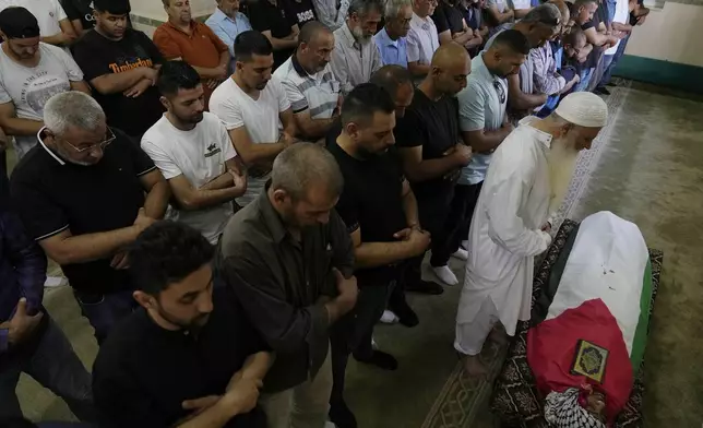 Palestinian mourners pray at the body of Mohammad Hoshiya, 12, during his funeral in the West Bank village of Qatana, southwest of Ramallah Saturday, June 22, 2024. The Palestinian Health Ministry said Hoshiya died from his wounds after being shot by Israeli forces in Ramallah last week. Commenting on the shooting, the Israeli army said its forces raided al-Amari refugee camp near Ramallah to arrest a suspect last Friday and then opened fire on a group of Palestinians who were pelting them with stones. (AP Photo/Nasser Nasser)