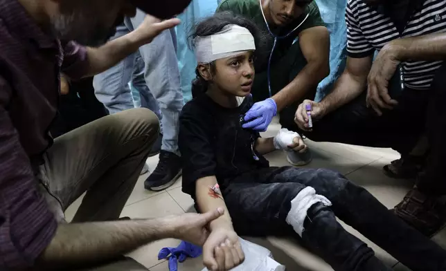 Palestinian medics treat a child wounded youth in the Israeli bombardment on a residential building owned by the Jabr family in the Bureij refugee camp, at al-Aqsa Martyrs Hospital in Deir al Balah, central Gaza Strip, Wednesday, June 12, 2024. (AP Photo/Saher Alghorra)