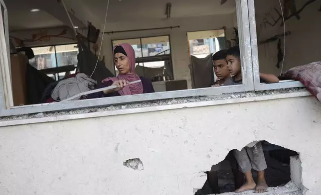 A Palestinian family inspects heavy damage to a UNRWA school sheltering displaced persons the day after a nearby house was targeted by Israeli bombardment in Khan Younis, southern Gaza Strip, Friday, June 21, 2024. (AP Photo /Jehad Alshrafi)