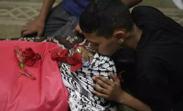 A Palestinian mourner takes the last look at the body of Mohammad Hoshiya, 12, during his funeral in the West Bank village of Qatana, southwest of Ramallah Saturday, June 22, 2024. The Palestinian Health Ministry said Hoshiya died from his wounds after being shot by Israeli forces in Ramallah last week. Commenting on the shooting, the Israeli army said its forces raided al-Amari refugee camp near Ramallah to arrest a suspect last Friday and then opened fire on a group of Palestinians who were pelting them with stones. (AP Photo/Nasser Nasser)