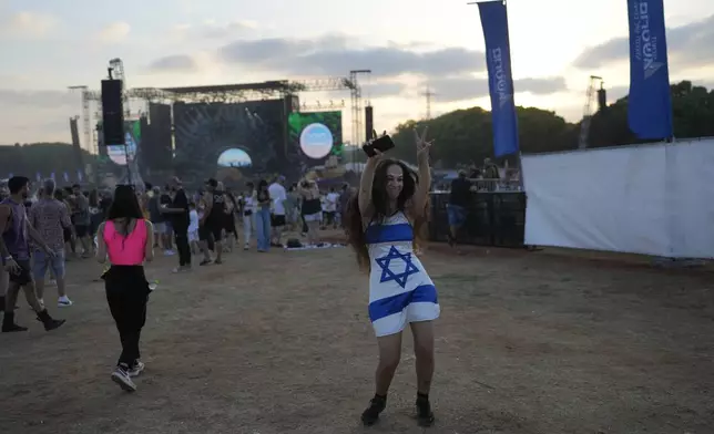 A woman wears a dress in the colors of the Israeli flag at the Nova Healing Concert in Tel Aviv, Israel, on Thursday, June 27, 2024. This was the first Tribe of Nova mass gathering since the Oct. 7, 2023 cross-border attack by Hamas that left hundreds at the Nova music festival dead or kidnapped to Gaza. (AP Photo/Ohad Zwigenberg)