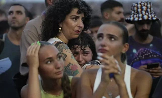 A young woman is comforted as she weeps at the Nova Healing Concert in Tel Aviv, Israel, on Thursday, June 27, 2024. This was the first Tribe of Nova mass gathering since the Oct. 7, 2023 cross-border attack by Hamas that left hundreds at the Nova music festival dead or kidnapped to Gaza. (AP Photo/Ohad Zwigenberg)