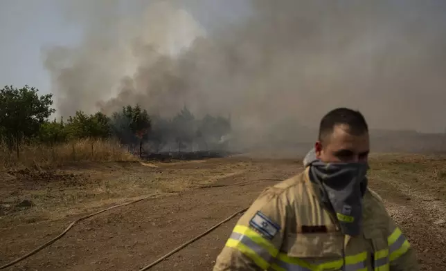 A firefighter walks near fire burning an area after a Lebanese shelling, in the Israeli-controlled Golan Heights, Thursday, June 13, 2024. (AP Photo/Leo Correa)