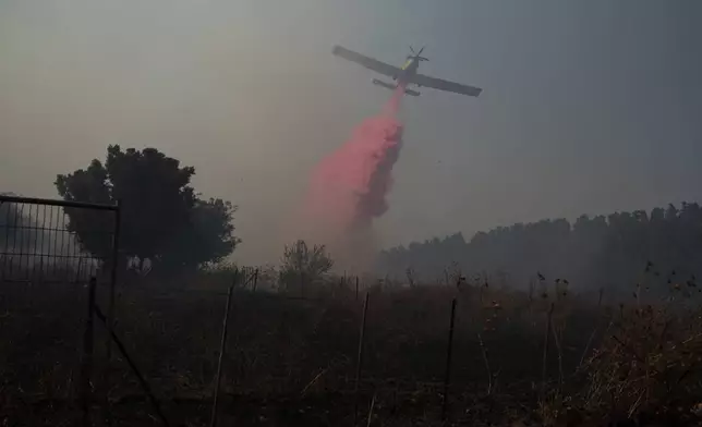 A plane uses a fire retardant to extinguish a fire burning in an area near the border with Lebanon, in Safed, northern Israel, Wednesday, June 12, 2024. Scores of rockets were fired from Lebanon toward northern Israel on Wednesday morning, hours after Israeli airstrikes killed four officials from the militant Hezbollah group including a senior military commander. (AP Photo/Leo Correa)