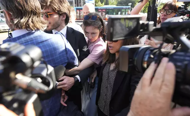 Amanda Knox arrives flanked by her husband Christopher Robinson, left, at the Florence courtroom in Florence, Italy, Wednesday, June 5, 2024. Amanda Knox returns to an Italian courtroom Wednesday for the first time in more than 12½ years to clear herself "once and for all" of a slander charge that stuck even after she was exonerated in the brutal 2007 murder of her British roommate in the idyllic hilltop town of Perugia. (AP Photo/Antonio Calanni)