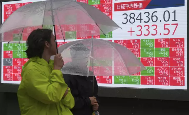 People walk in the rain in front of an electronic stock board showing Japan's Nikkei 225 index at a securities firm Tuesday, June 18, 2024, in Tokyo. Shares were mostly higher in Asia on Tuesday after U.S. stocks rallied to more records, with gains for technology companies pushing the benchmarks higher. (AP Photo/Eugene Hoshiko)