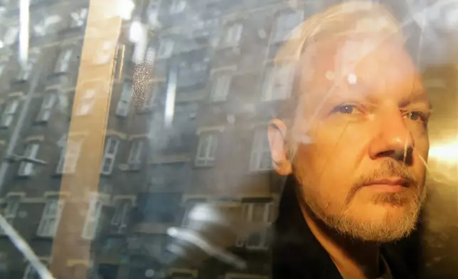 FILE - Buildings are reflected in the window as WikiLeaks founder Julian Assange is taken from court, where he appeared on charges, Wednesday May 1, 2019 of jumping British bail seven years ago, in London. Assange will plead guilty to a felony charge in a deal with the U.S. Justice Department that will free him from prison and resolve a long-running legal saga over the publication of a trove of classified documents. (AP Photo/Matt Dunham, File)