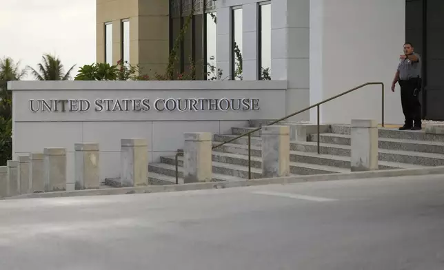 An security officer gestures to journalists who are waiting outside the United States courthouse where WikiLeaks founder Julian Assange is expected to enter a plea deal, in Saipan, Mariana Islands, Wednesday, June 26, 2024. (AP Photo/Eugene Hoshiko)