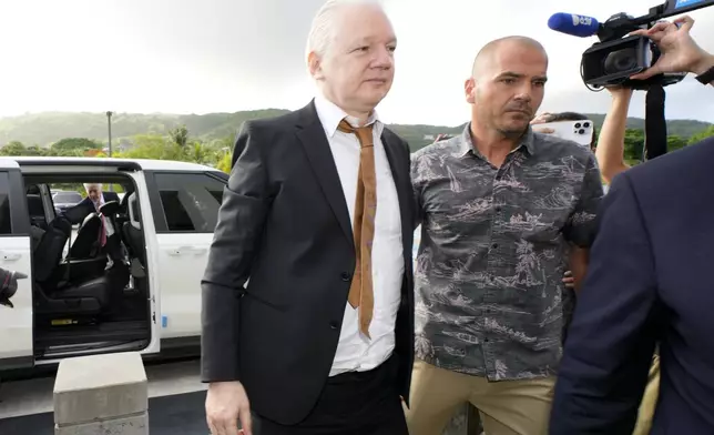 WikiLeaks founder Julian Assange, left, is escorted as he arrives at the United States courthouse where he is expected enter a plea deal, in Saipan, Mariana Islands, Wednesday, June 26 2024. (AP Photo/Eugene Hoshiko)