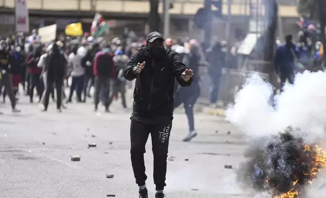 Protesters scatter as police fire tear gas at them during a protest over proposed tax hikes in a finance bill in downtown Nairobi, Kenya Tuesday, June. 25, 2024. (AP Photo/Brian Inganga)