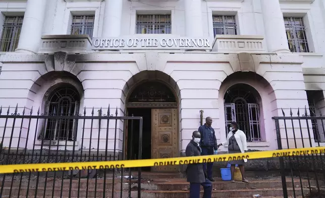 Nairobi county workers stand in front of the governor's office, which was burned during yesterday's protest over proposed tax hikes in a finance bill in downtown Nairobi, Kenya Wednesday, June 26, 2024. Thousands of protesters stormed and burned a section of Kenya's parliament Tuesday to protest tax proposals. Police responded with gunfire and several protesters were killed. (AP Photo/Brian Inganga)