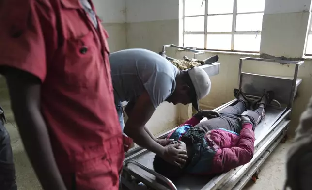 A relative closes the eyes of a protester allegedly shot by police at the Nairobi funeral home, Kenya Wednesday, June 26, 2024. Thousands of protesters stormed and burned a section of Kenya's parliament Tuesday to protest tax proposals. Police responded with gunfire and several protesters were killed. (AP Photo/Brian Inganga)