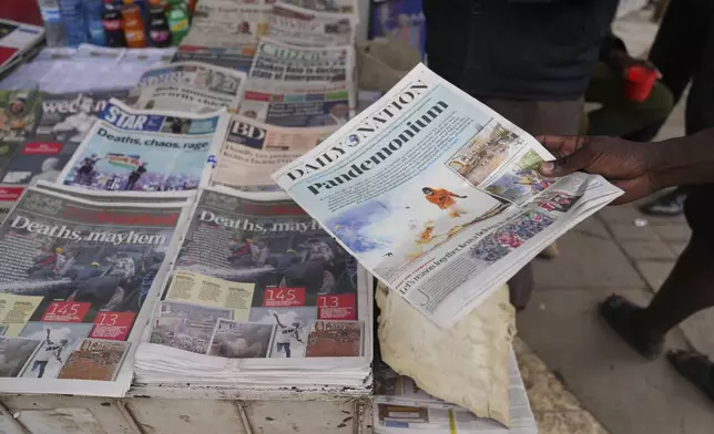 Kenyans discuss yesteday's protest as they read newspapers from a street vendor in downtown Nairobi, Kenya Wednesday, June 26, 2024. Thousands of protesters stormed and burned a section of Kenya's parliament Tuesday to protest tax proposals. Police responded with gunfire and several protesters were killed. (AP Photo/Brian Inganga)