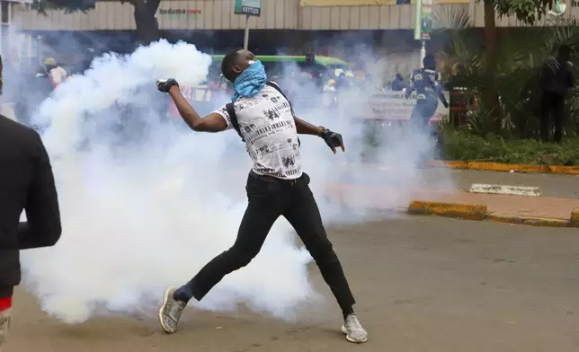 A protesters throws back a teargas canister at police officers during a protest over proposed tax hikes in a finance bill that is due to be tabled in parliament in Nairobi, Kenya, Thursday, June 20, 2024. (AP Photo/ Andrew Kasuku)