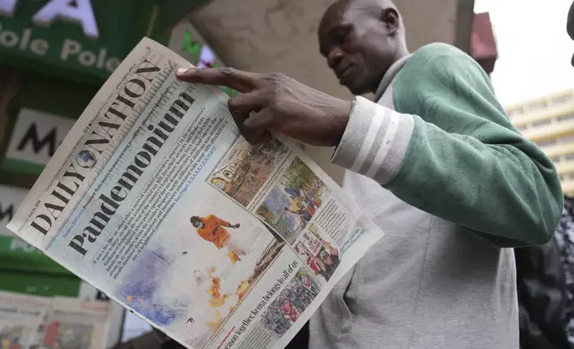 A man reads about yesterday's protest in a newspaper in downtown Nairobi, Kenya Wednesday, June 26, 2024. Thousands of protesters stormed and burned a section of Kenya's parliament Tuesday to protest tax proposals. Police responded with gunfire and several protesters were killed. (AP Photo/Brian Inganga)