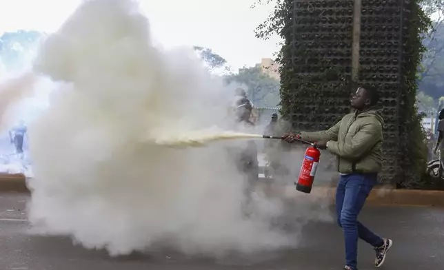 A protester uses a fire extinguisher during a protest over proposed tax hikes in a finance bill that is due to be tabled in parliament in Nairobi, Kenya, Thursday, June 20, 2024. (AP Photo/ Andrew Kasuku)