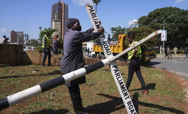 Nairobi county staff repair a street sign in downtown Nairobi, Kenya, Wednesday, June 26, 2024. Thousands of protesters stormed and burned a section of Kenya's parliament Tuesday to protest tax proposals. Police responded with gunfire and several protesters were killed. (AP Photo/Brian Inganga)