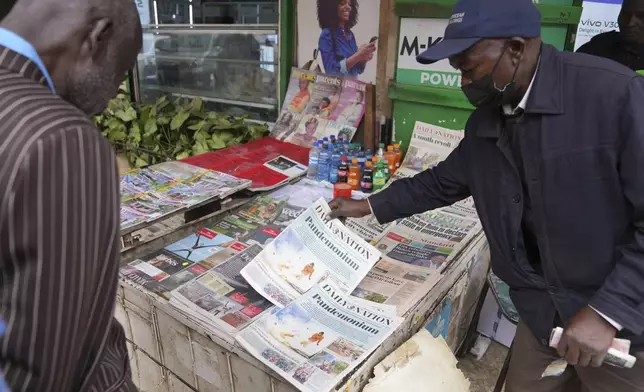 Kenyans discuss yesteday's protest as they read newspapers from a street vendor in downtown Nairobi, Kenya Wednesday, June 26, 2024. Thousands of protesters stormed and burned a section of Kenya's parliament Tuesday to protest tax proposals. Police responded with gunfire and several protesters were killed. (AP Photo/Brian Inganga)