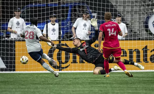Vancouver Whitecaps' Levonte Johnson (28) is stopped by St. Louis City goalkeeper Ben Lundt, center, as Tomas Totland (14) watches during the first half of an MLS soccer match Saturday, June 29, 2024, in Vancouver, British Columbia. (Ethan Cairns/The Canadian Press via AP)